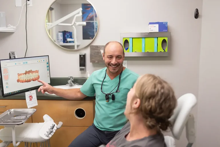 Dr. Joshua Clarkman of Roots Dental in Bellingham showing a patient a 3D digital model of teeth during a dental consultation.