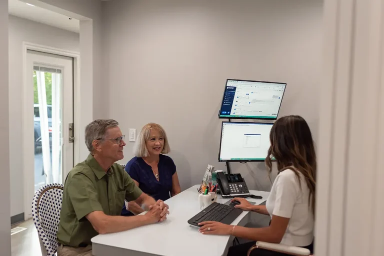 Dental team member at Roots Dental in Bellingham, WA discussing treatment options with two patients during a private consultation.
