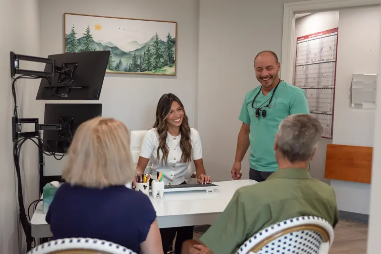 Dr. Joshua Clarkman and a team member at Roots Dental in Bellingham, WA smiling during a friendly dental membership plans discussion. No Insurance? No Problem!
