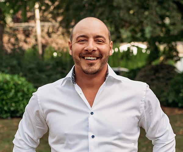 Dr. Joshua Clarkman, dentist at Roots Dental in Bellingham, smiling in a professional outdoor portrait.