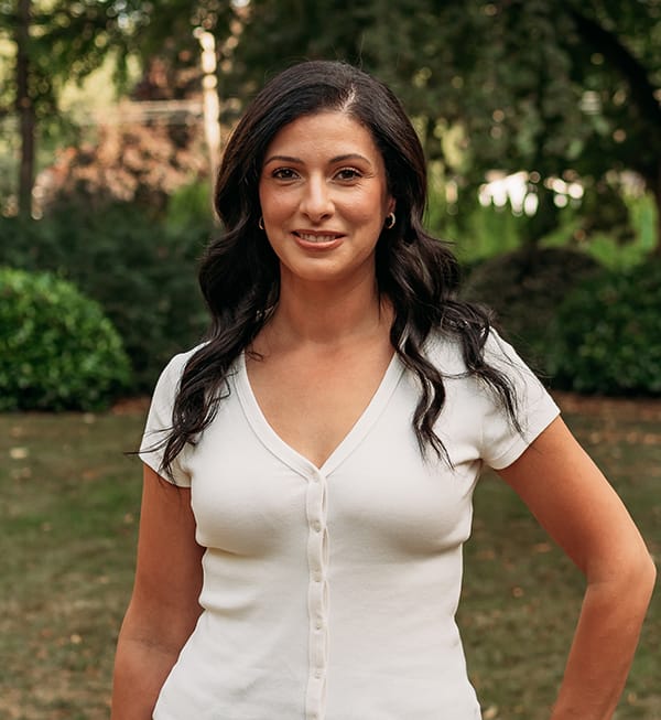 Female Roots Dental team member in Bellingham smiling outdoors, dedicated to patient-focused dental care.